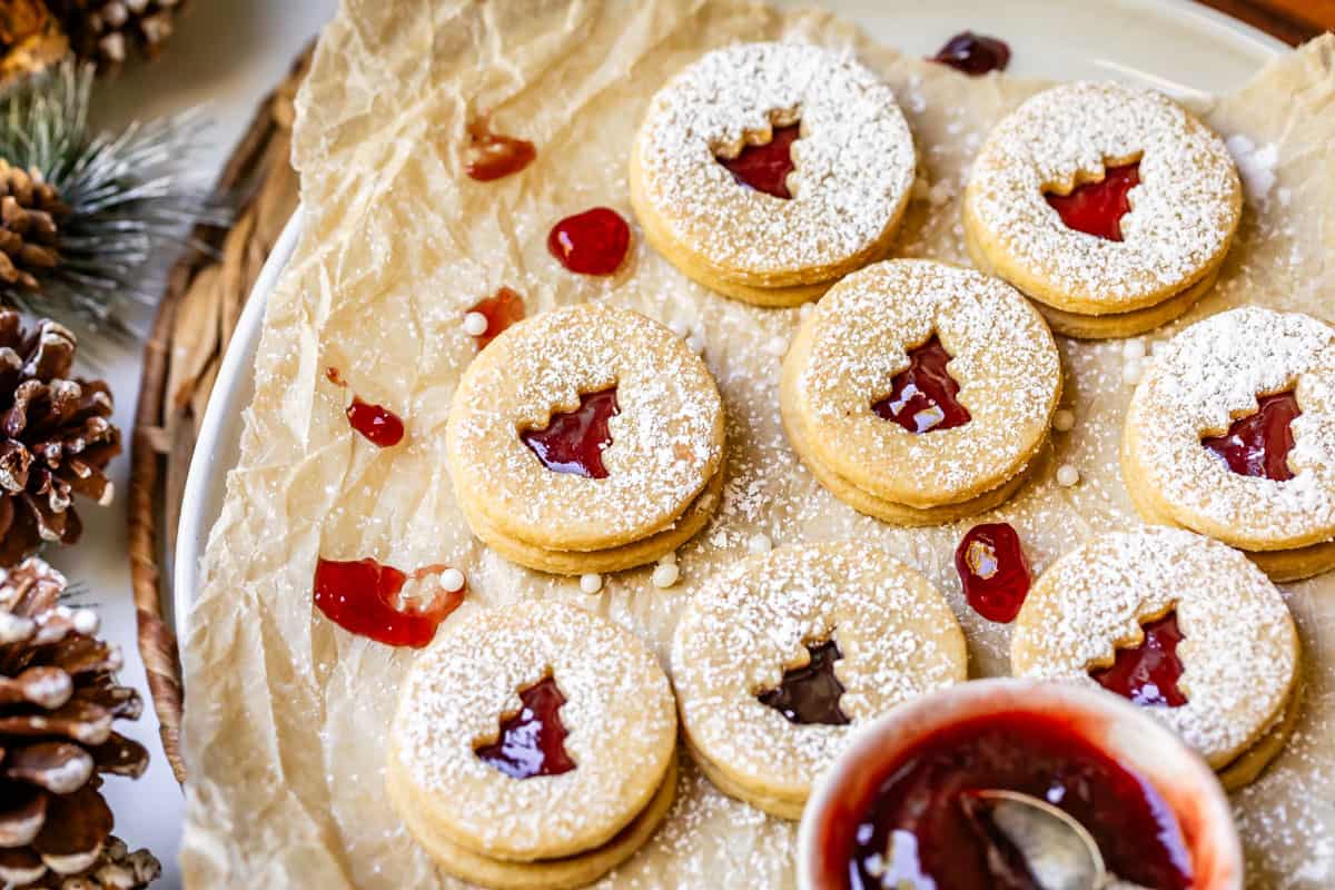 platter topped with parchment paper and several linzer cutout cookies.