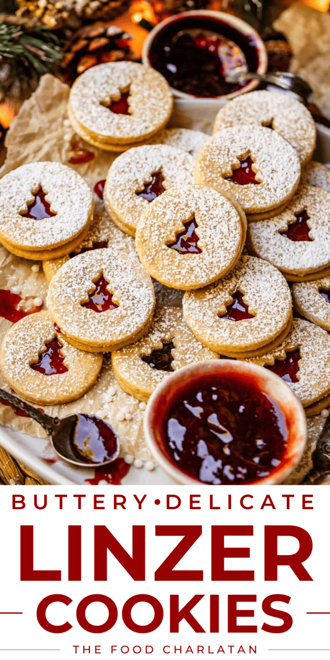plate of over a dozen linzer cookies with christmas cut outs and jam.