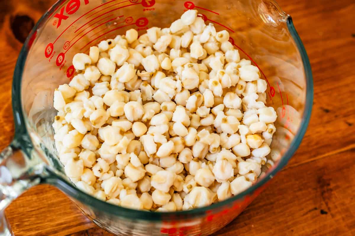 large liquid measuring cup full of hominy, which is dried and then cooked corn.