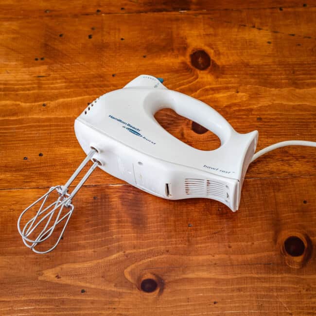 Hamilton beach hand mixer on wooden table.