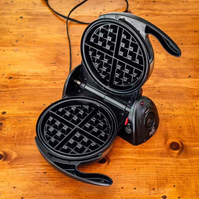 Belgian flip waffle maker on wooden table.