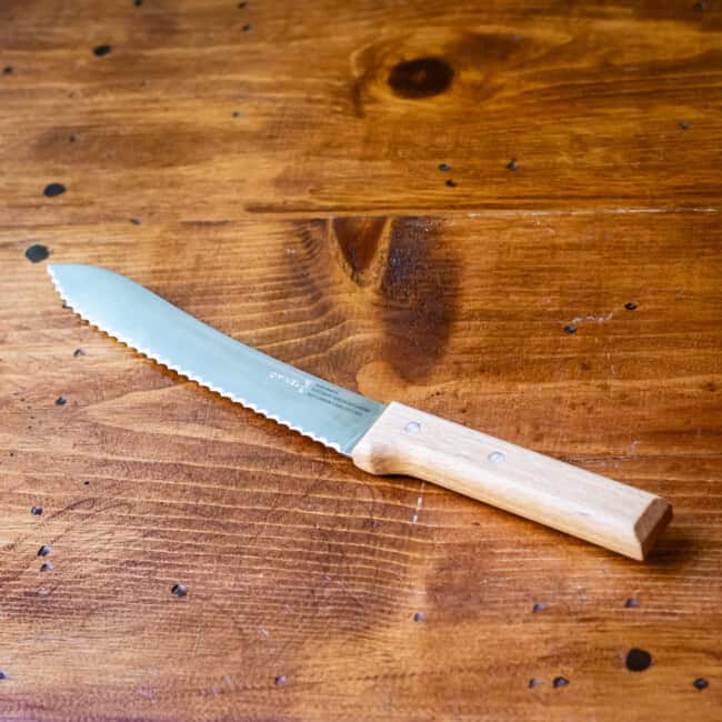 Opinel bread knife on wooden table.