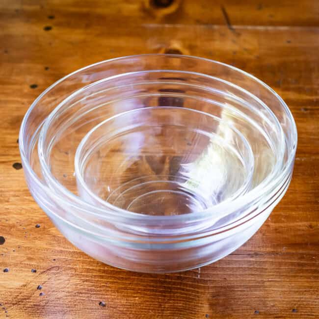 Nested clear glass mixing bowls on wooden table.