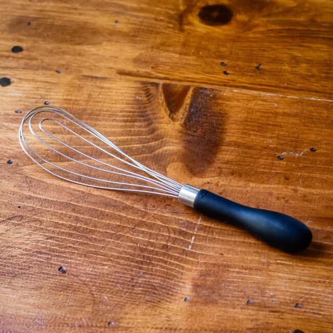 Flat whisk on wooden table.