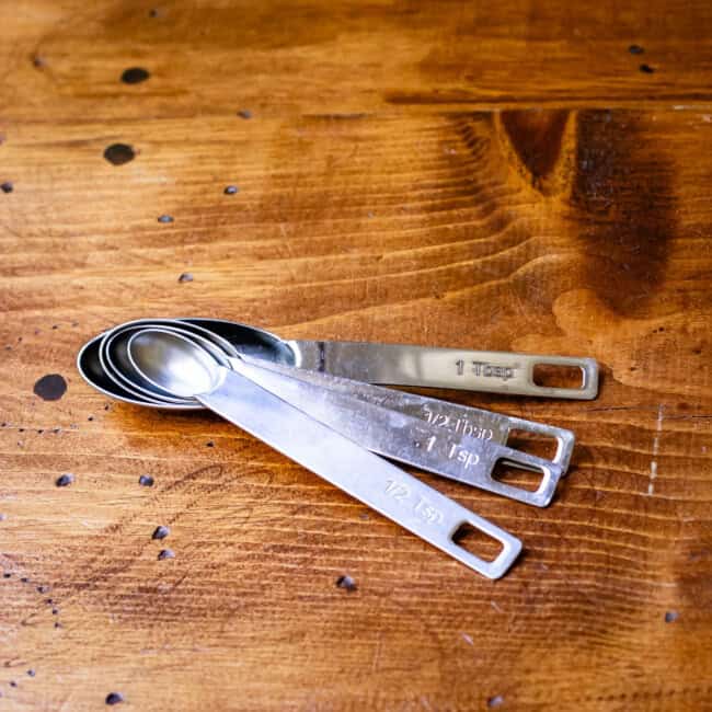 Nested measuring spoons for 1/2 tsp, 1 tsp, 1/2 tbsp, & 1 tbsp on wood table.