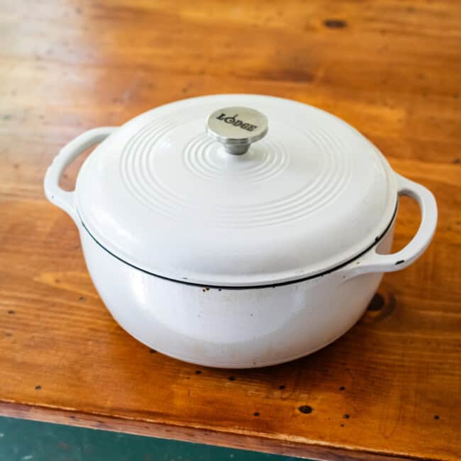 Lodge enameled dutch oven on wooden table.