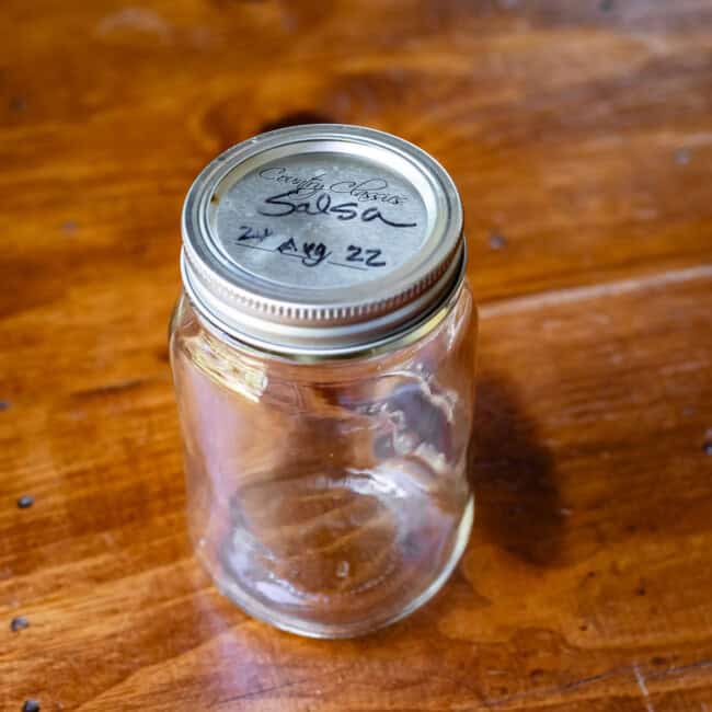 Glass quart-size mason jar with metal lid on wooden table.