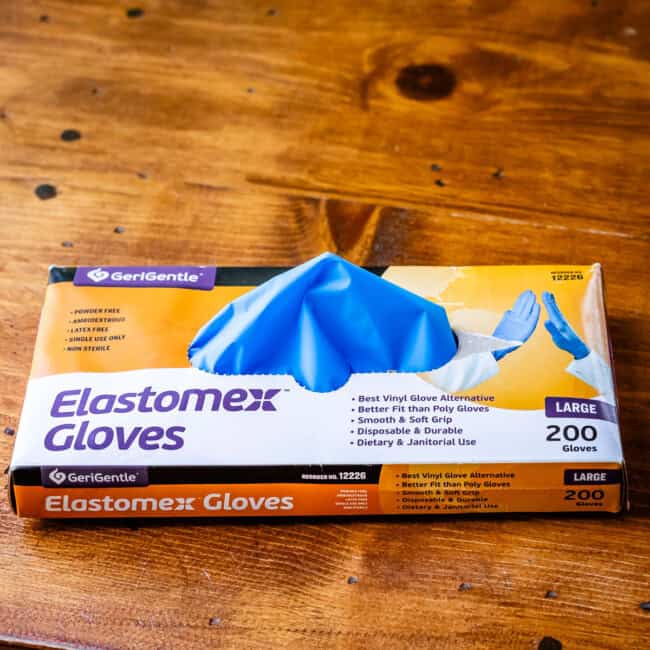 Box of disposable vinyl gloves on wooden table.