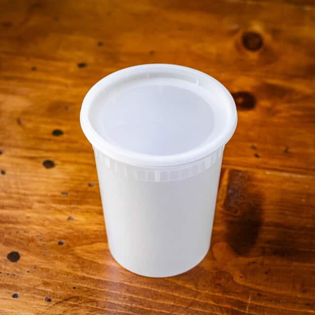 Plastic soup takeaway container on wooden table.