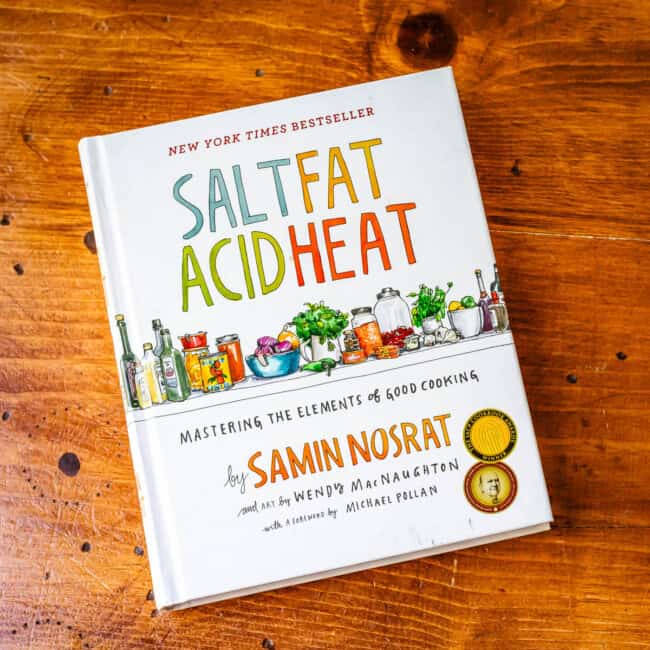 Copy of cookbook salt fat acid heat by Samin Nosrat on wooden table.