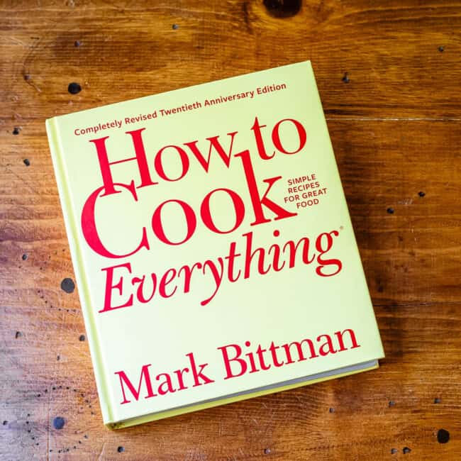 Copy of cookbook how to cook everything by Mark Bittman on wooden table.