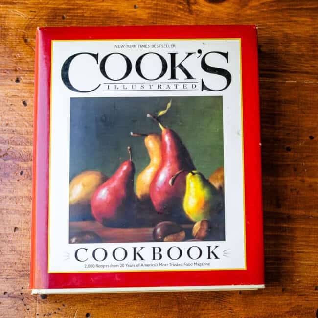 Copy of Cook's Illustrated cookbook on wooden table.