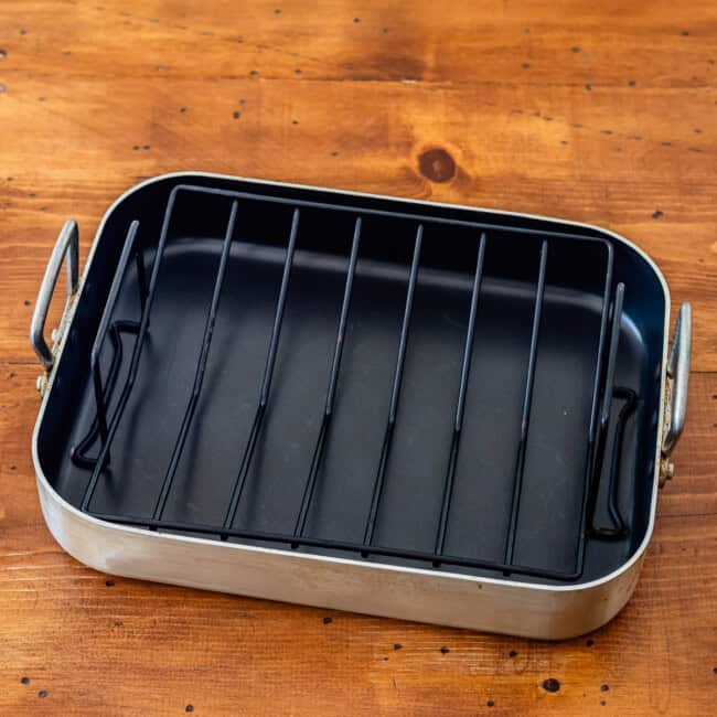 Roasting pan and rack on wooden table.