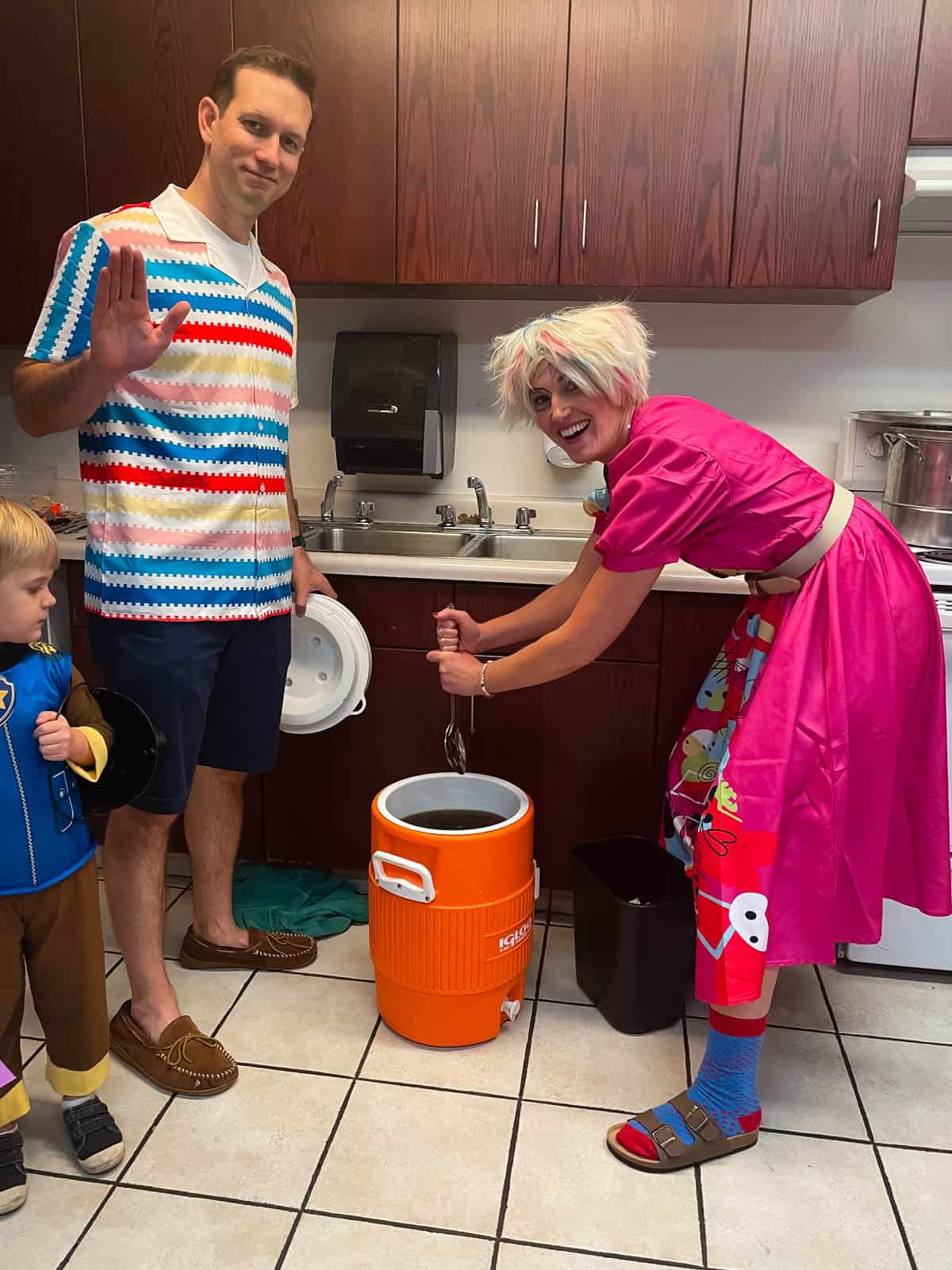 Woman dressed as weird barbie stirring 5 gallon jug