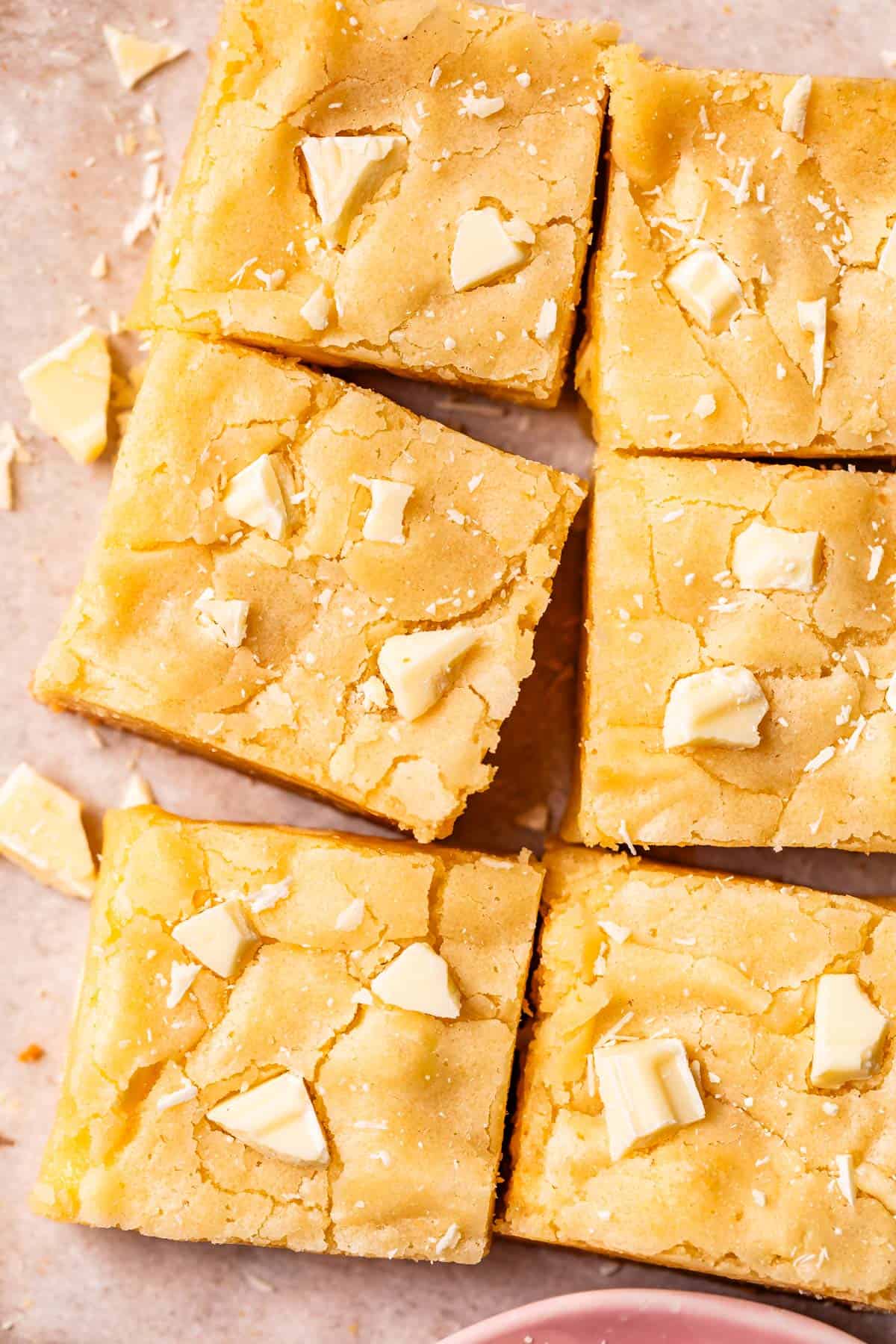 6 cut squares of white chocolate brownies on top of parchment paper.