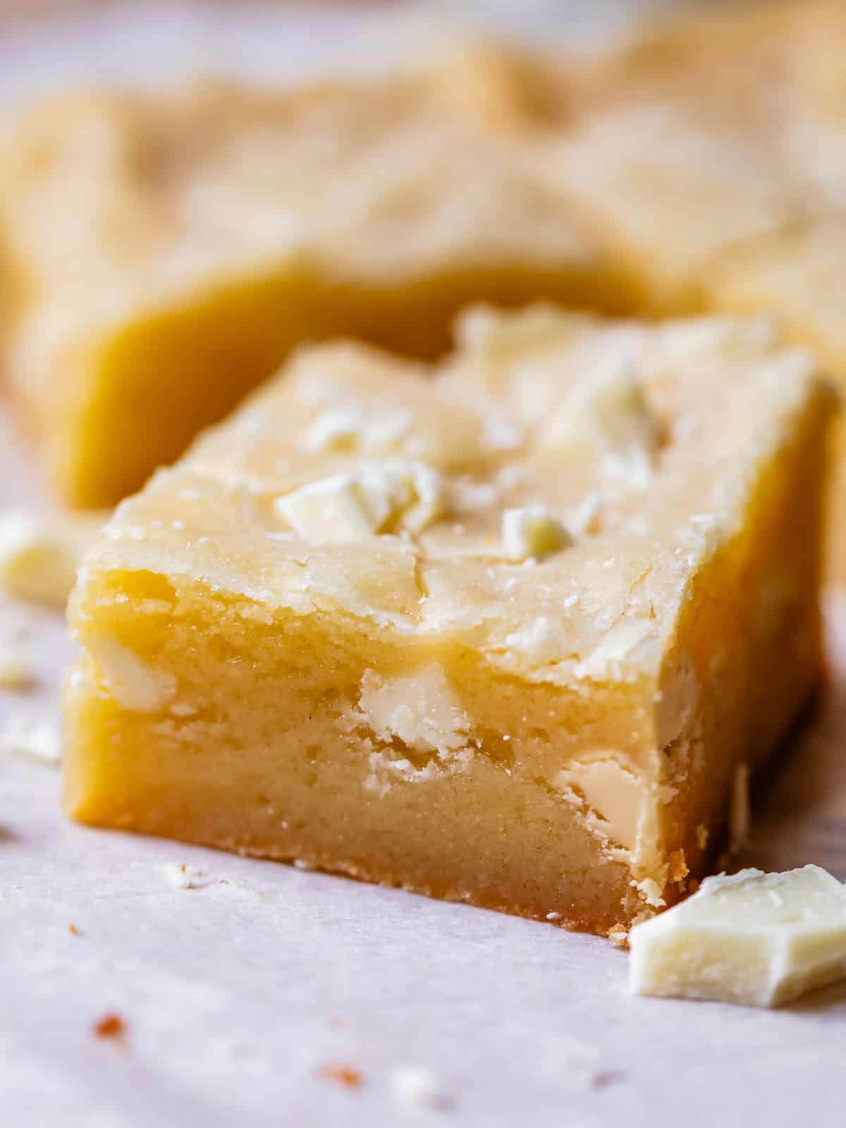 a retangular piece of white brownies with white chocolate in the brownie and on top.