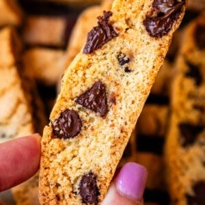 finger and thumb holding a baked biscotti with chocolate chips in it.