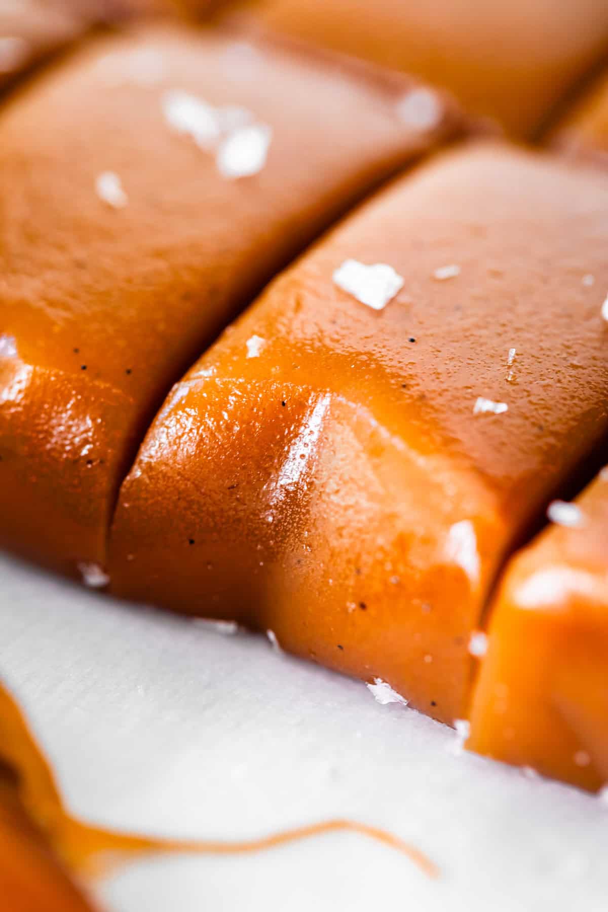 close up of soft caramel cut into pieces with flaky salt on top.
