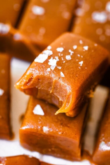 soft, salted caramel candy rectangle with a bite taken from it, stacked on another rectangle.