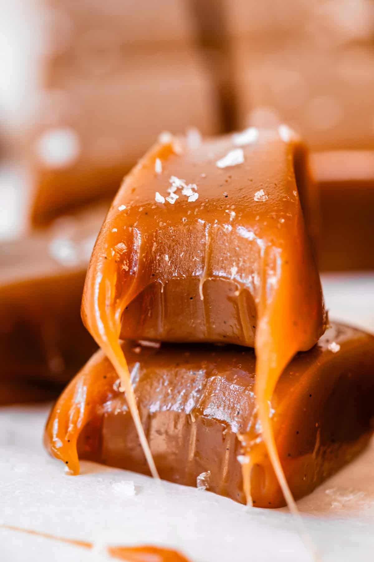 Caramel candy made with cream with a bite in it stacked on one made with evaporated milk.
