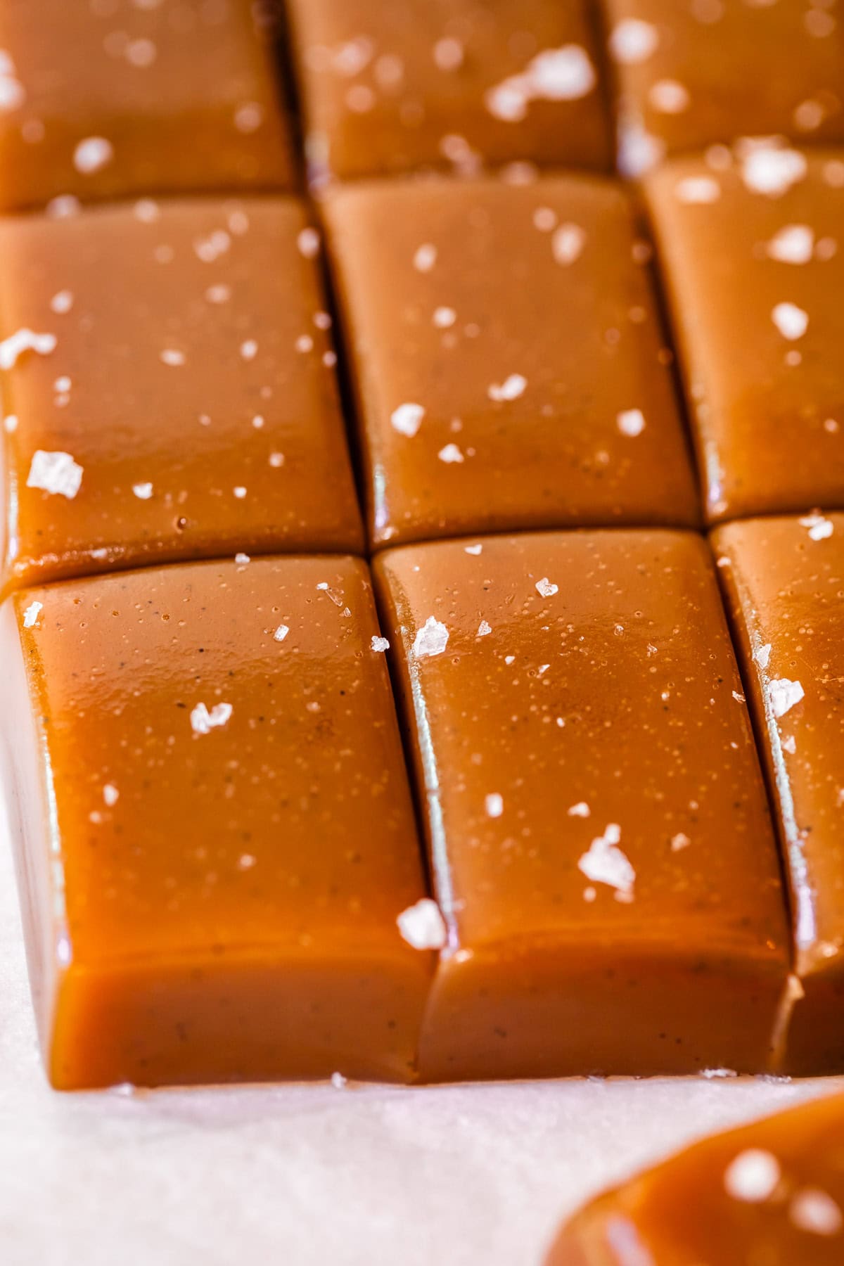 soft caramel candy cut into pieces with flaky salt garnish on top.