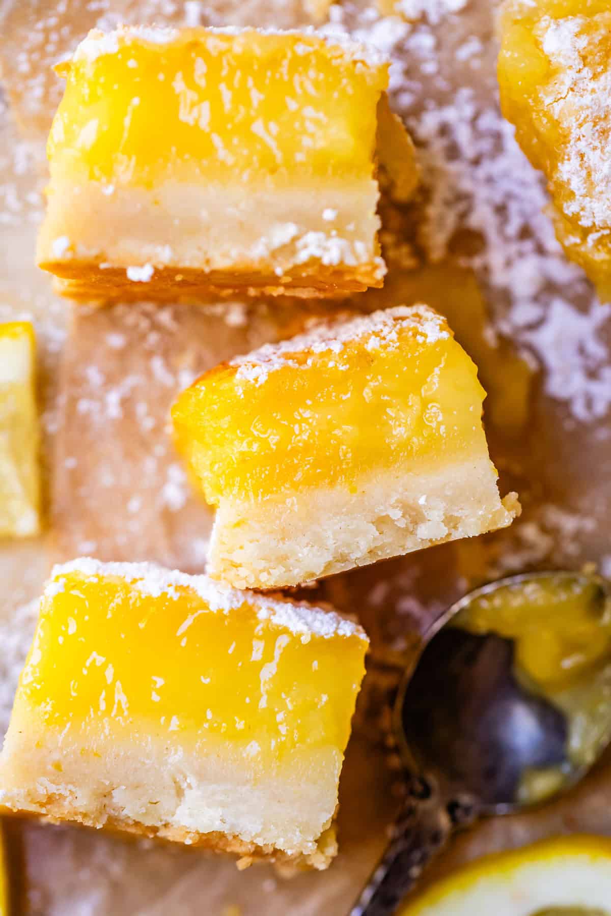 sideways view of three lemon bars showing the lemon custard and shortbread layers.