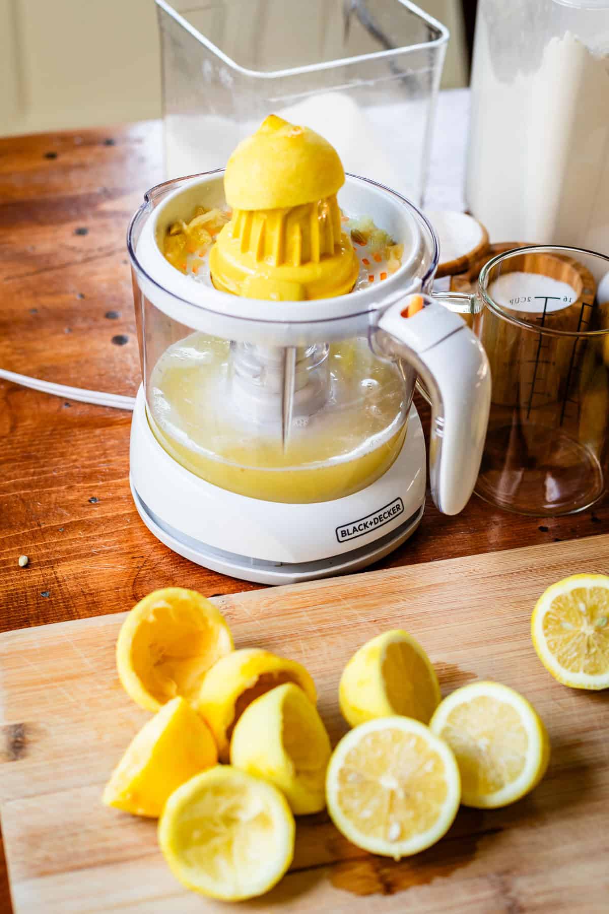 lemon on an electric juicer with several lemon halves on a cutting board.