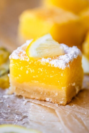 close up of a lemon bar perfectly balanced with crust, filling, and powdered sugar topping.