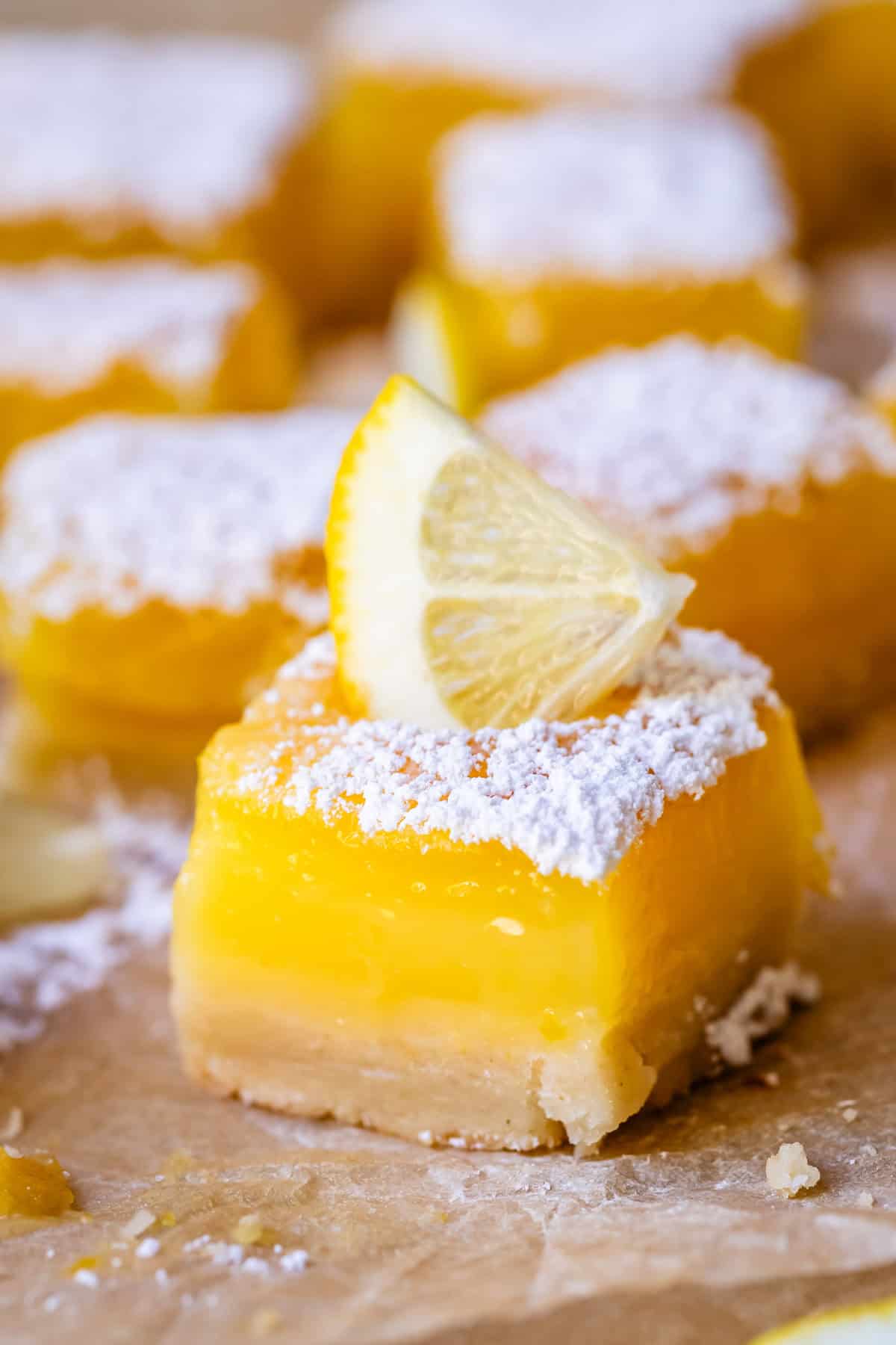 a lemon bar square dusted with powdered sugar and garnished with lemon.