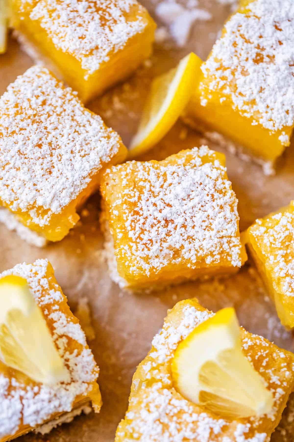 close up of a few lemon bars cut into squares with powdered sugar and lemon.