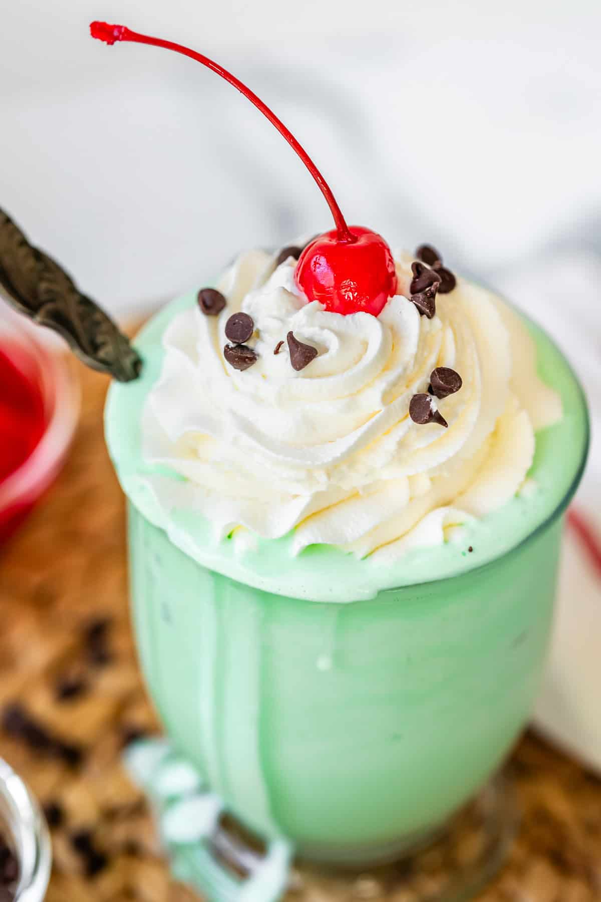 glass with shake, topped with piped whipped cream, a cherry, and chocolate chips.