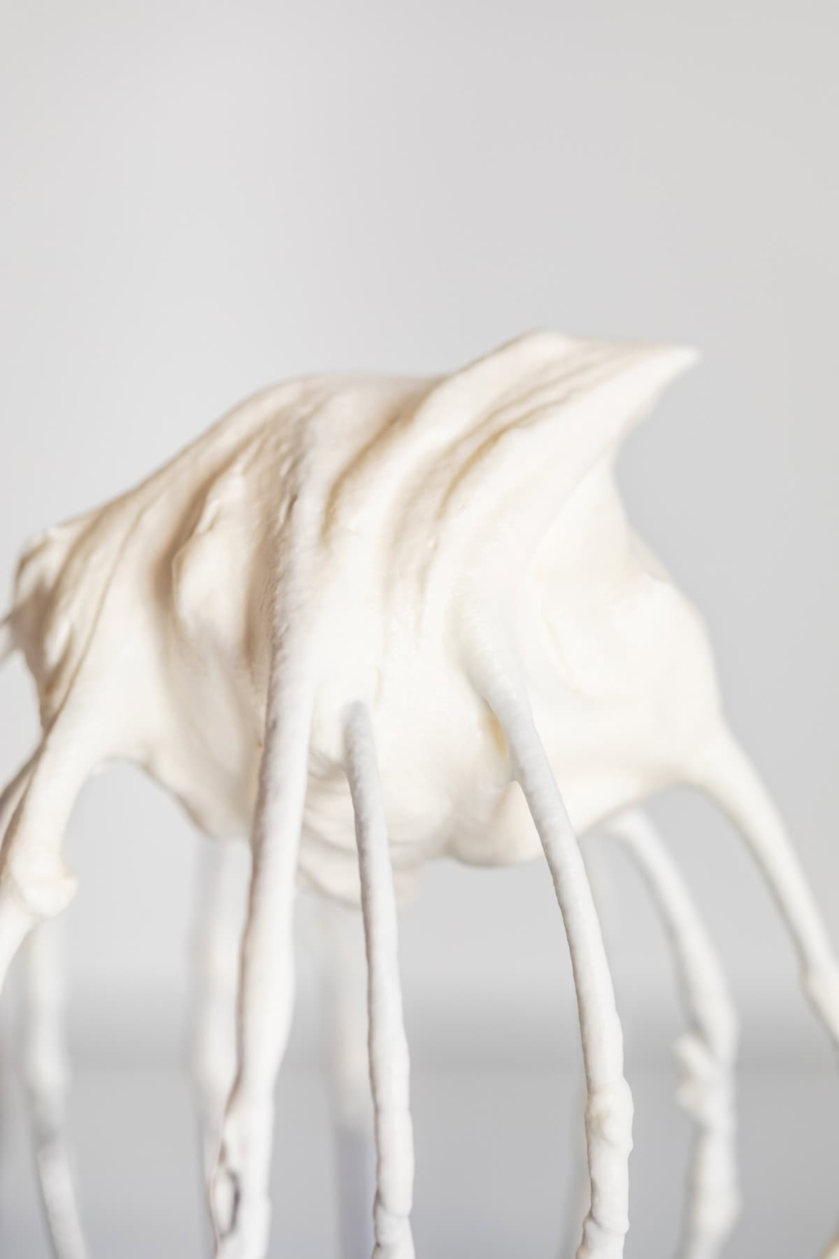 stiff peak of whipped cream on an upside down kitchen aide whisk attachment.