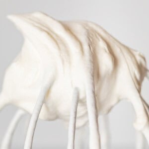close up of whipped cream in a stiff peak on a whisk attachment.
