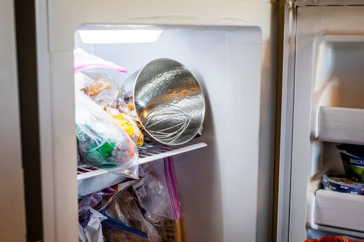 refrigerator with a metal mixing bowl and whisk attachment in it.