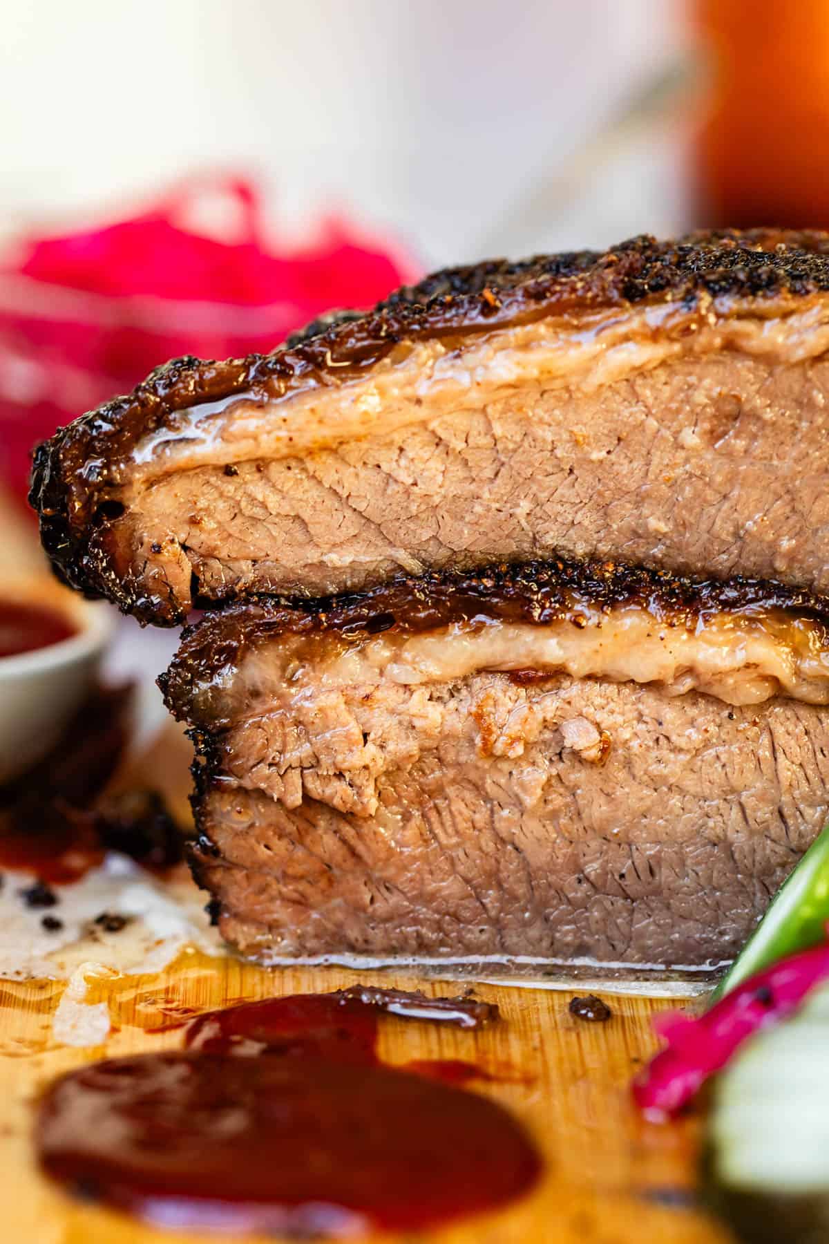 Two cuts of beef brisket stacked together on bamboo cutting board.