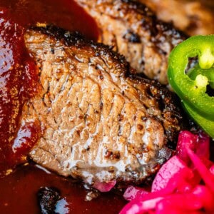 Juicy slices of beef brisket with bbq sauce drizzled on with jalapeño and pickled onions.