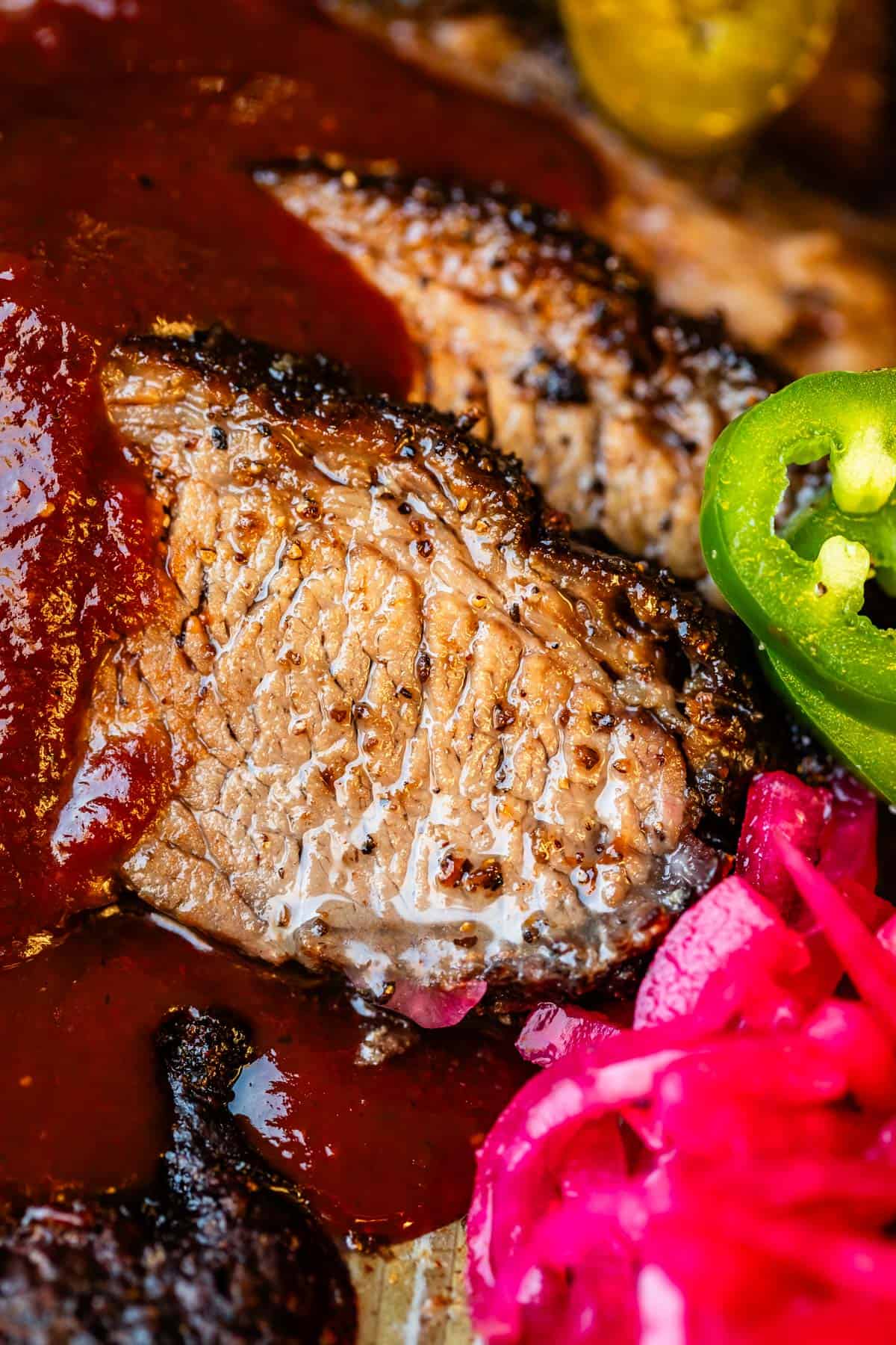 Juicy slices of beef brisket with bbq sauce drizzled on with jalapeño and pickled onions.