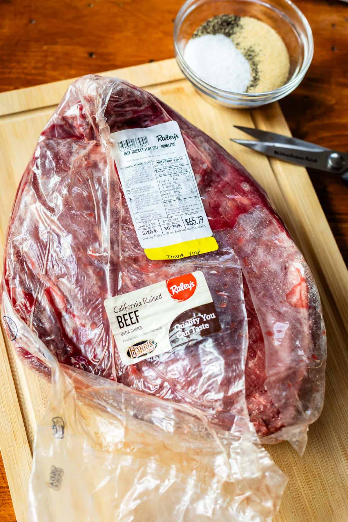 raw brisket in its vacuum sealed packaging sitting on a cutting board.