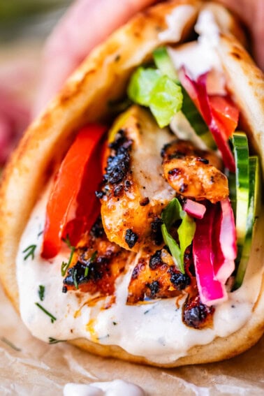 close up of chicken shawarma in naan with cucumber, onion, and garlic sauce.
