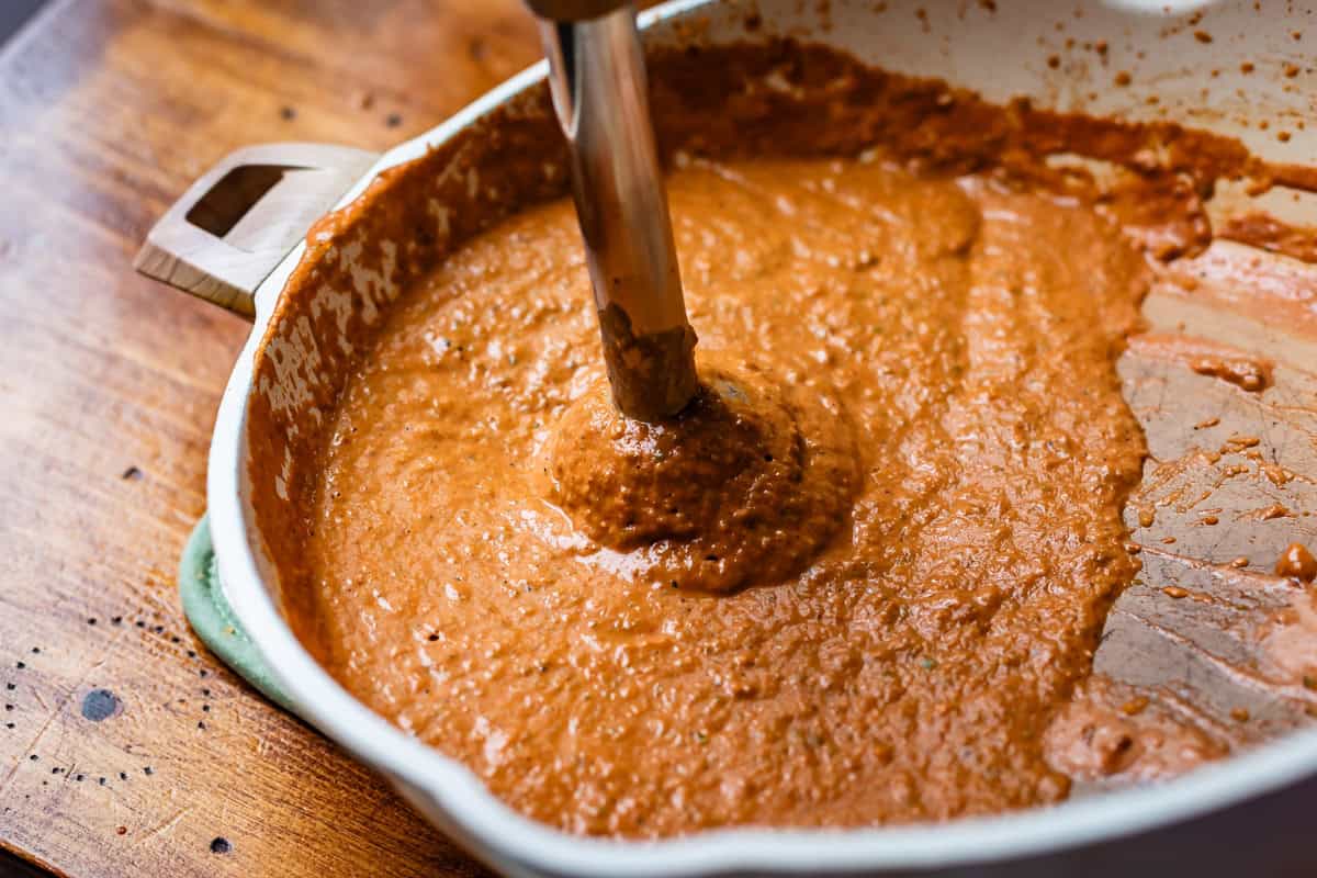 immersion blender in pan with now blended and smooth sauce.