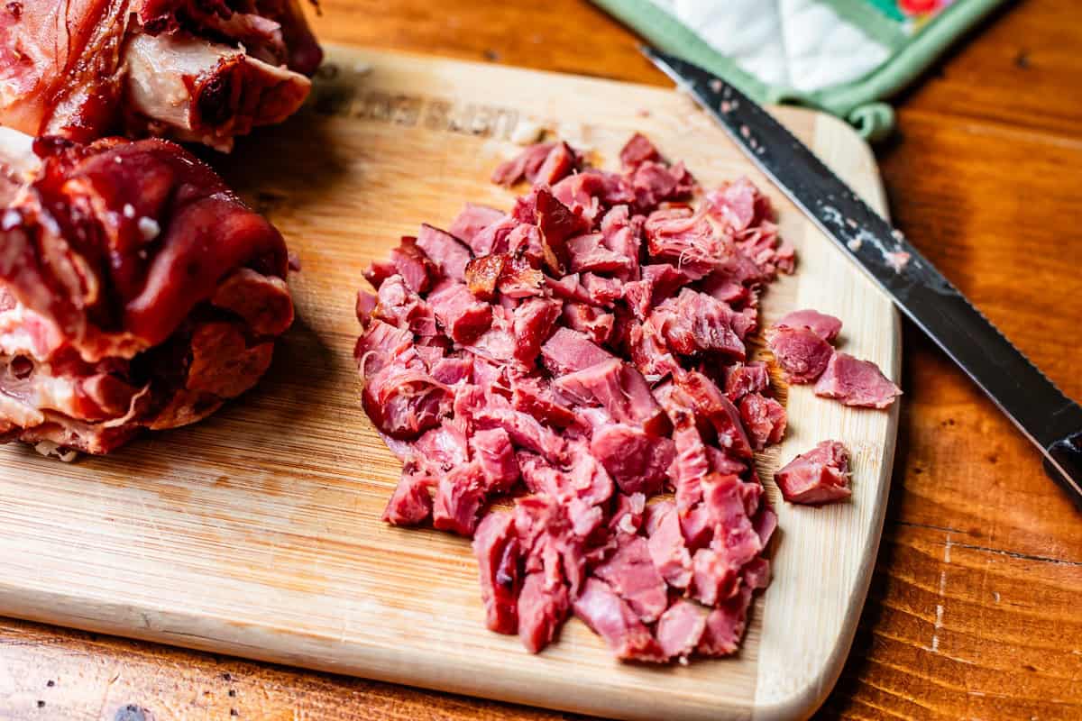cooked ham hocks on cutting board, with some chopped up into bite size pieces.