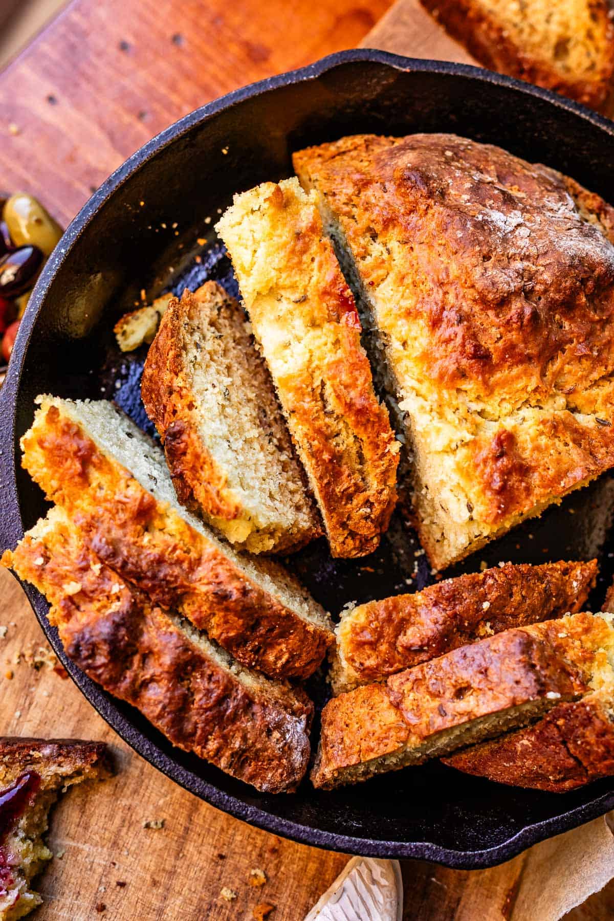 Overhead shot of loaf of Irish soda bread cut into many different slices sitting in cast iron skillet.