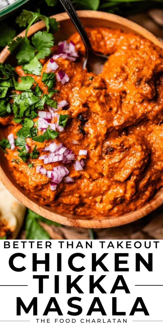 wooden bowl full of chicken tikka masala with red onions and cilantro.
