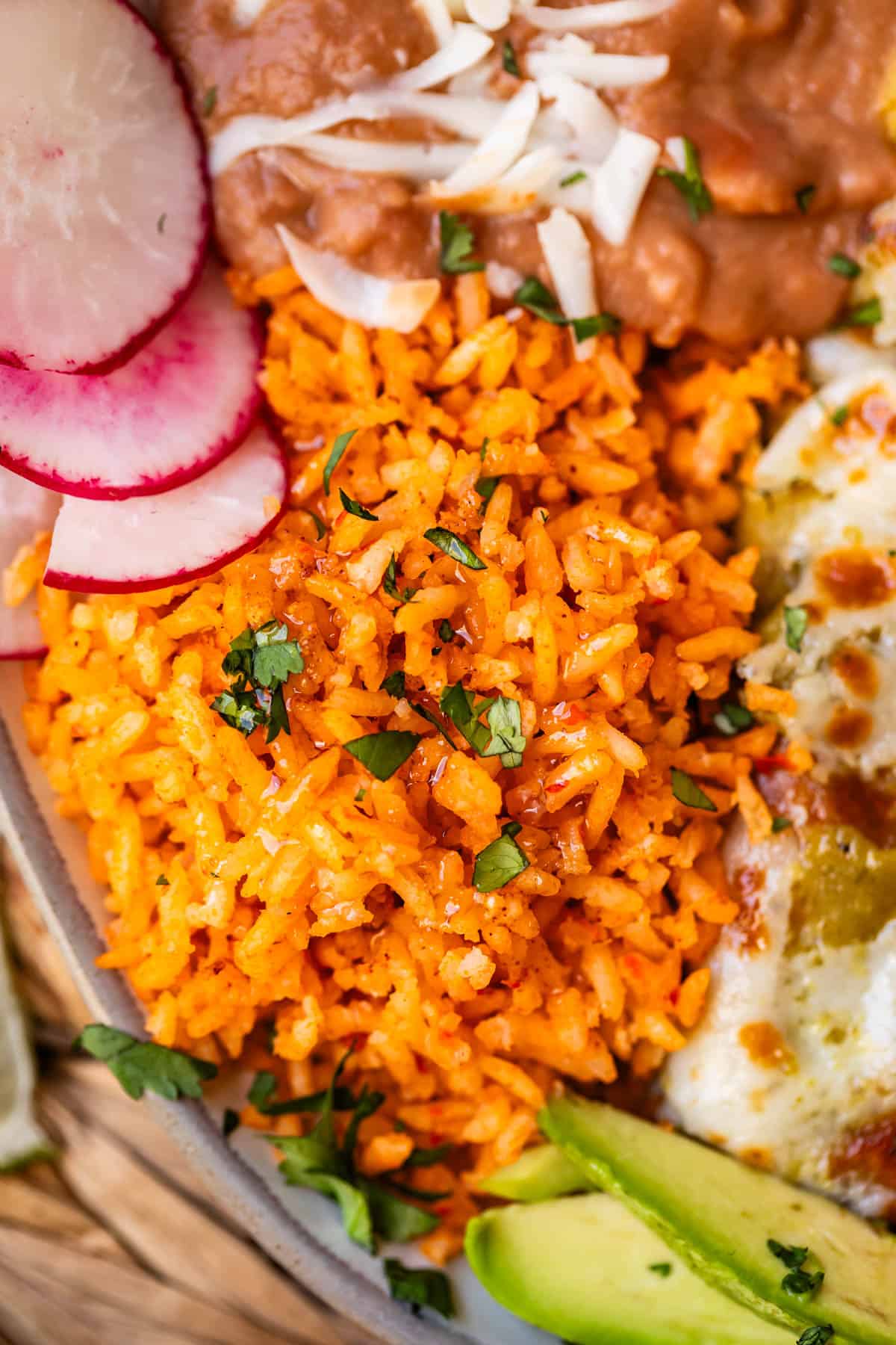 close up of the Mexican rice on a plate next to enchiladas and beans.