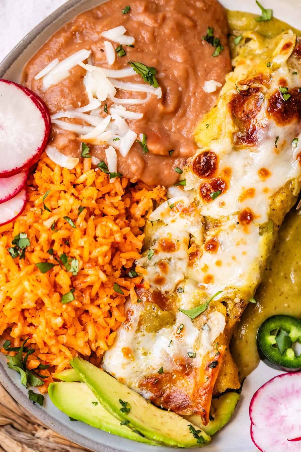 plate filled with salsa verde enchiladas, refried beans, and Mexican rice.