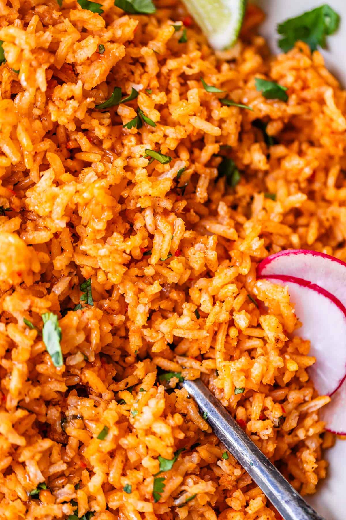 looking straight down view at a large amount of Mexican rice with radish and lime garnish.