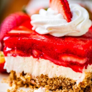 perfectly cut square of jello pretzel salad with whipped cream & strawberry garnish.
