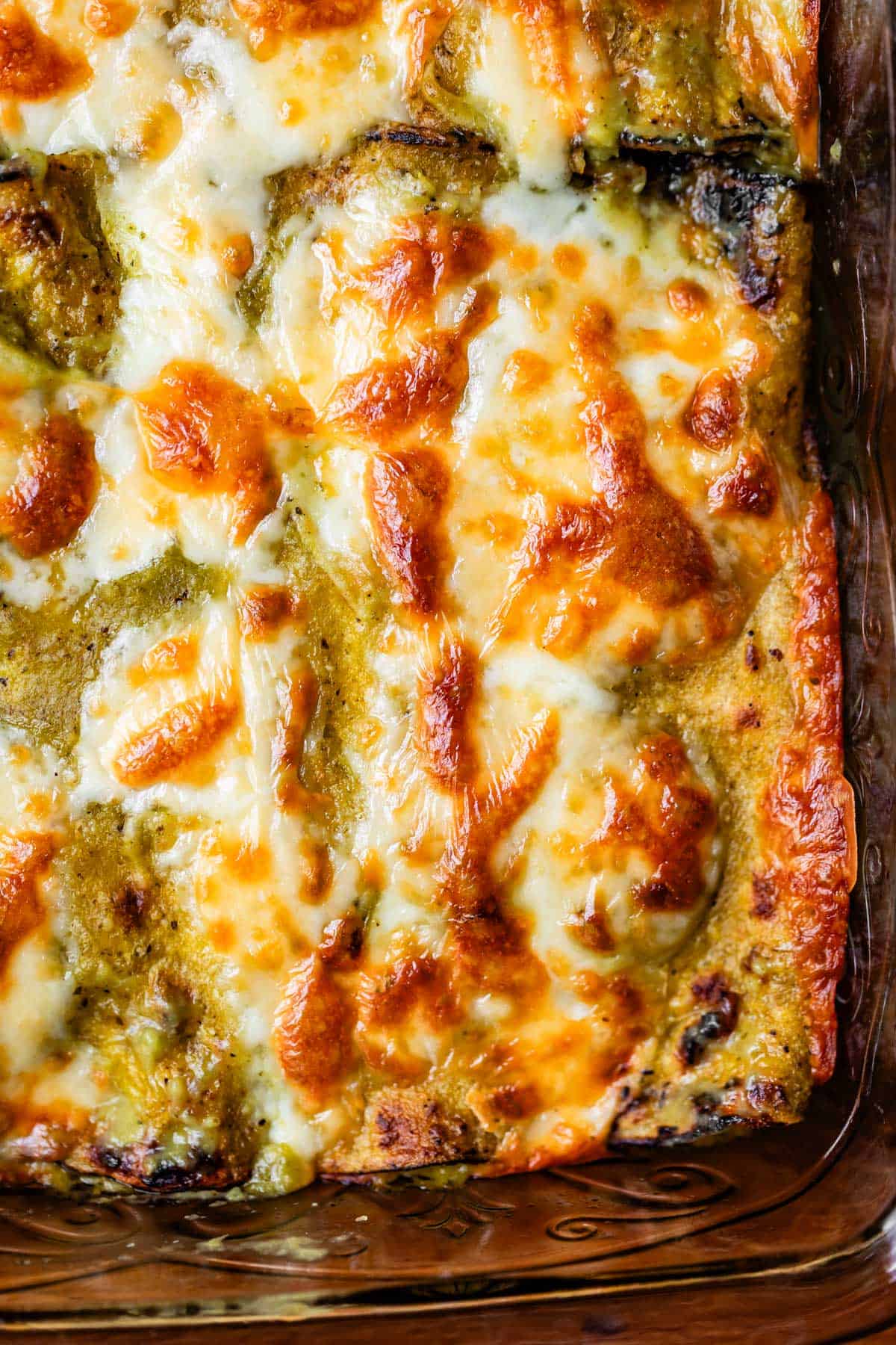 overhead shot of chicken enchiladas with green sauce and broiled cheese.
