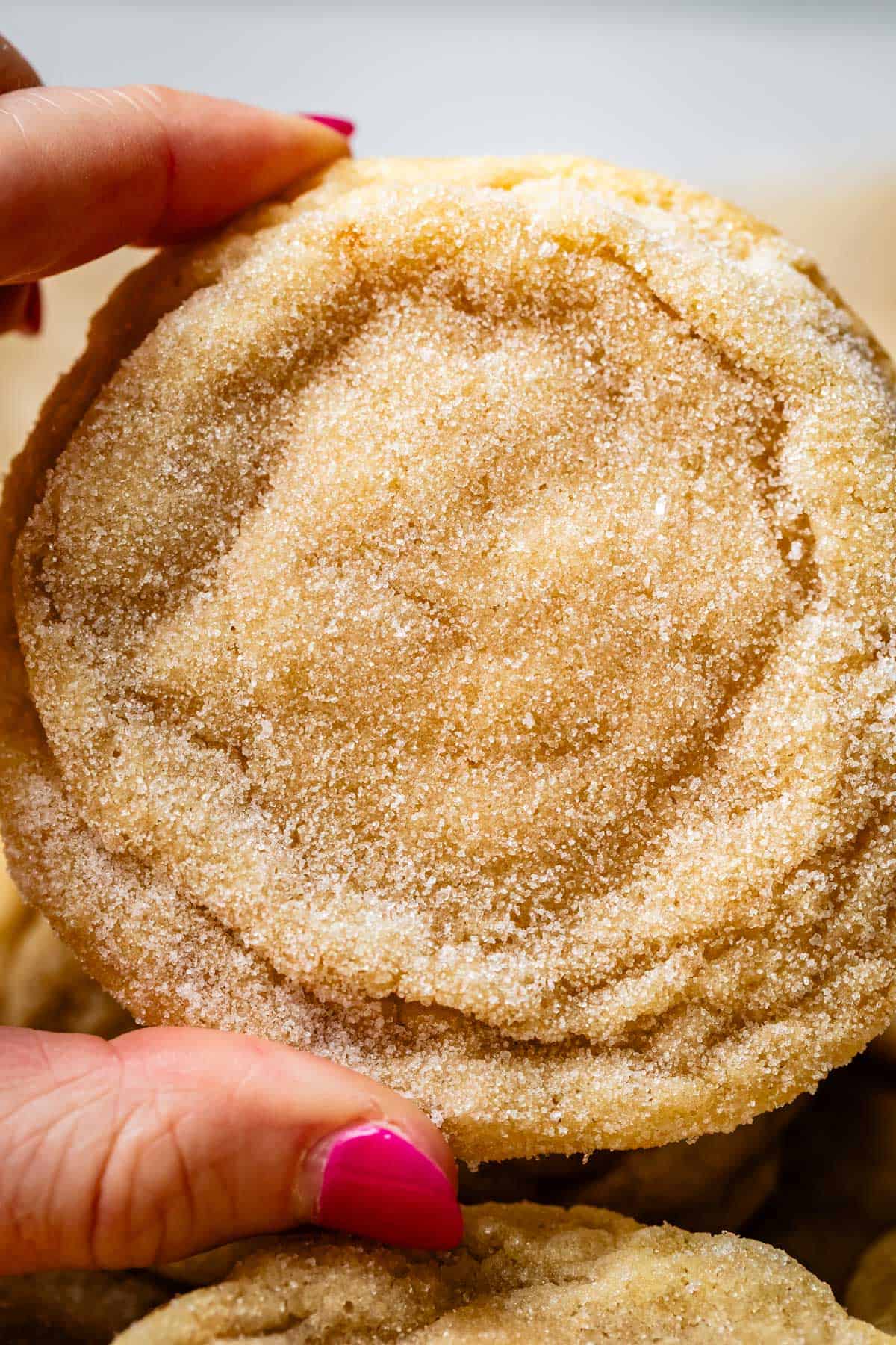 finger and thumb holding up a very close up view of drop sugar cookies.