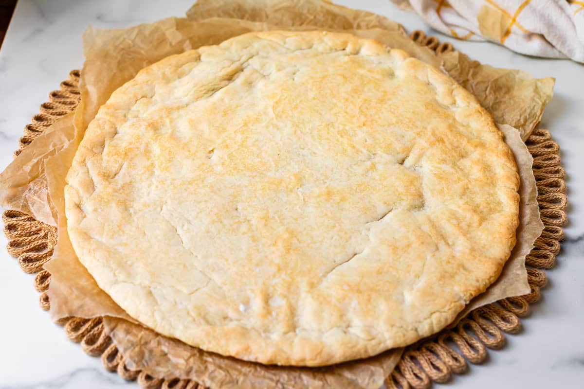 a circle of baked cookie dough crust on parchment paper on a place mat.